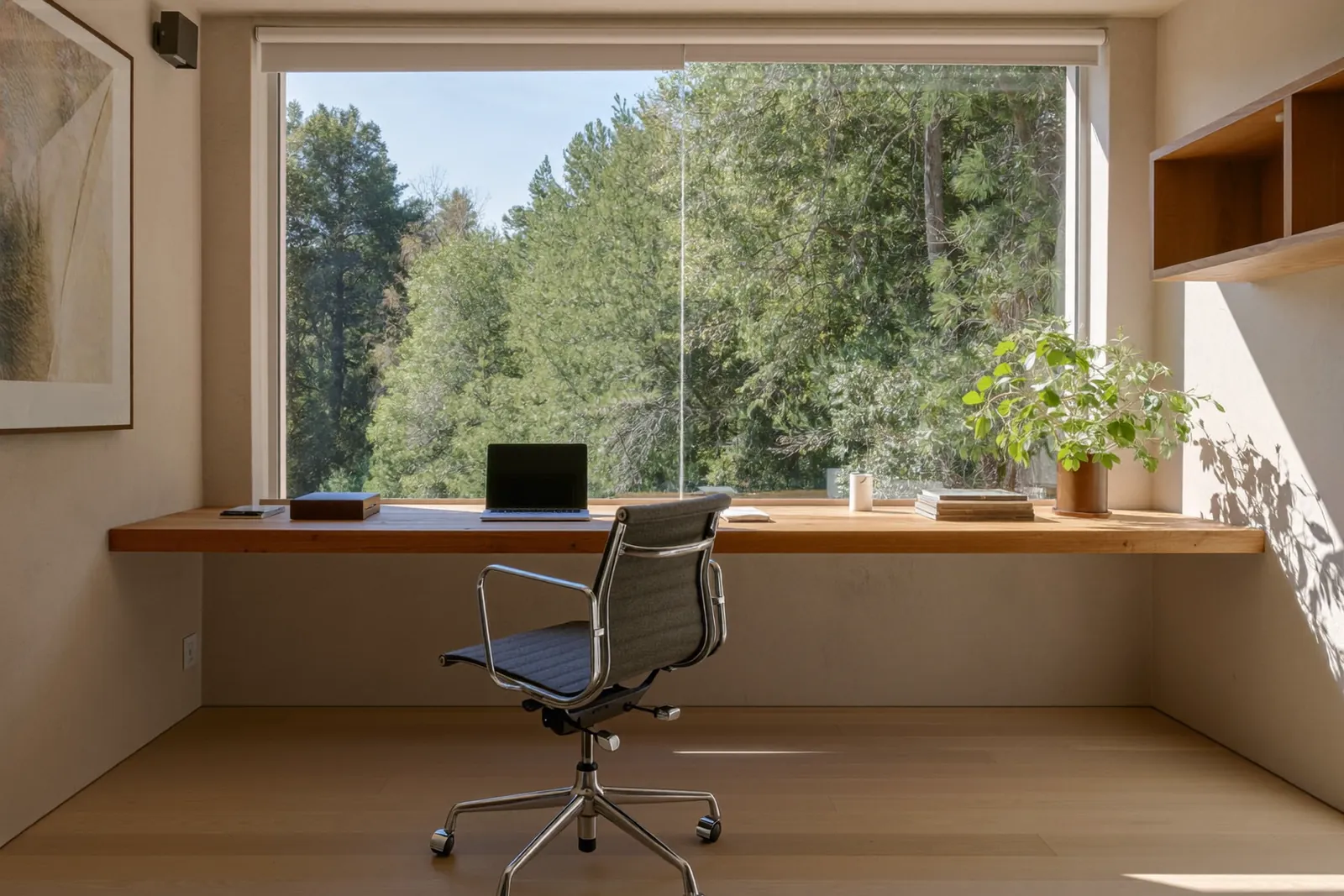 Helles Arbeitszimmer mit Schreibtisch, Laptop und Fenster mit Blick ins Grüne